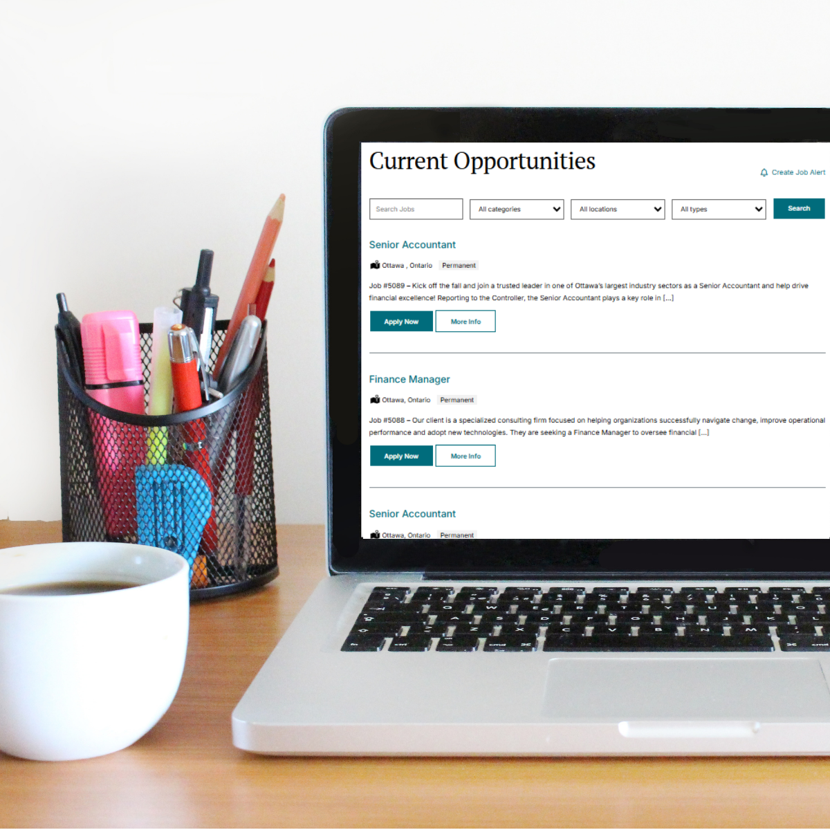 Laptop displaying a 'Current Opportunities' job listings page on a desk, with a pen cup and coffee mug nearby